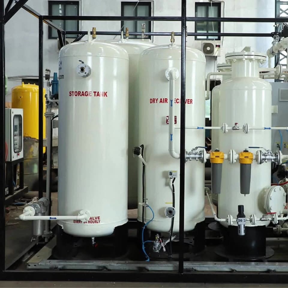 A skid-mounted oxygen plant inside a steel frame: two tall white pressure vessels marked Storage Tank and Dry Air Receiver, with filter housings, valves and pipework.